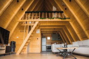 Un intérieur en bois comprenant une chambre en mezzanine, une cuisine et un coin salon.