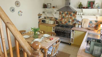 Una cocina con una mesa de comedor, sillas, estufa, microondas y diversos utensilios de cocina.