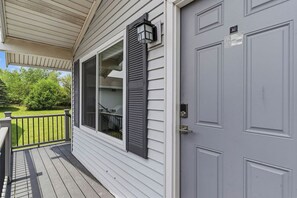 A house with a porch, a grey door, and a window with shutters.