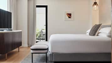 Una habitación de hotel moderna con cama, televisión, una mesita y vistas al exterior.