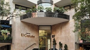 A modern hotel entrance with a curved balcony, a staircase leading to the entrance, and potted plants. - Kimpton El Castelar Polanco by IHG (Mexico City)