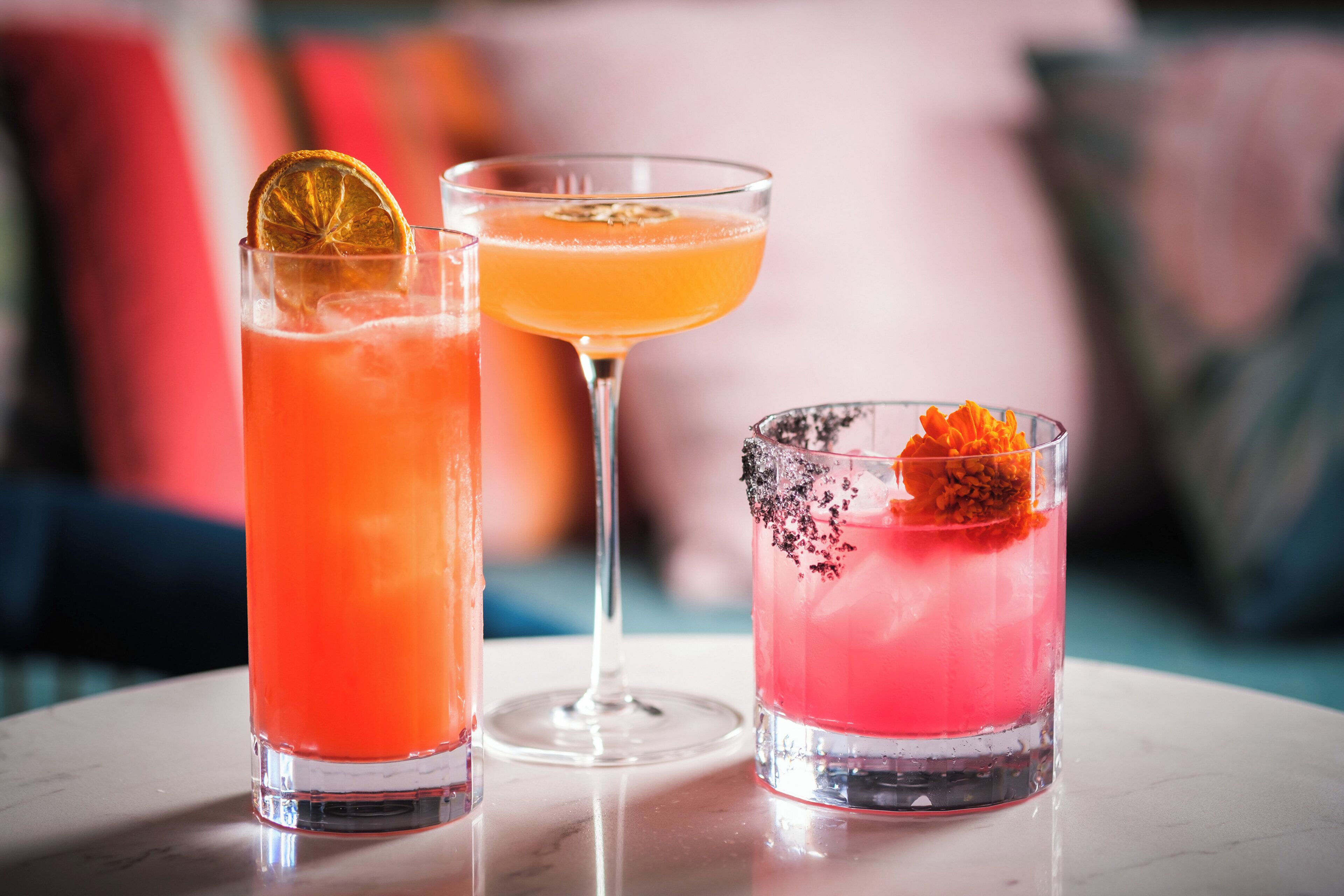 Três cocktails sobre uma mesa com fundo desfocado.