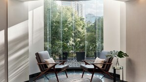 A corner room with a large window, two chairs, a small table, and a potted plant. - Kimpton El Castelar Polanco by IHG (Mexico City)
