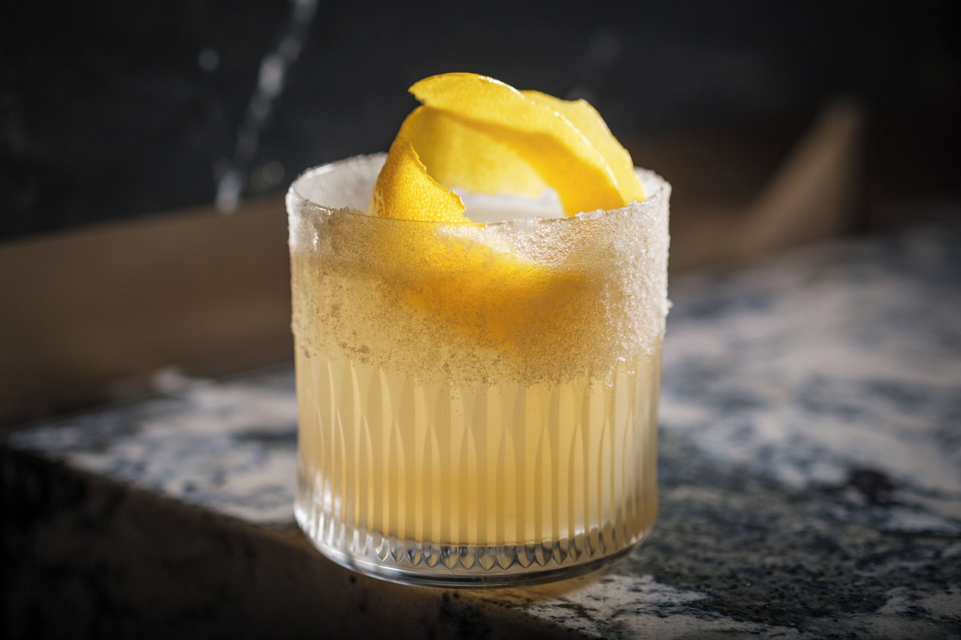 Un verre contenant une boisson et une tranche de fruit, posé sur une surface texturée.