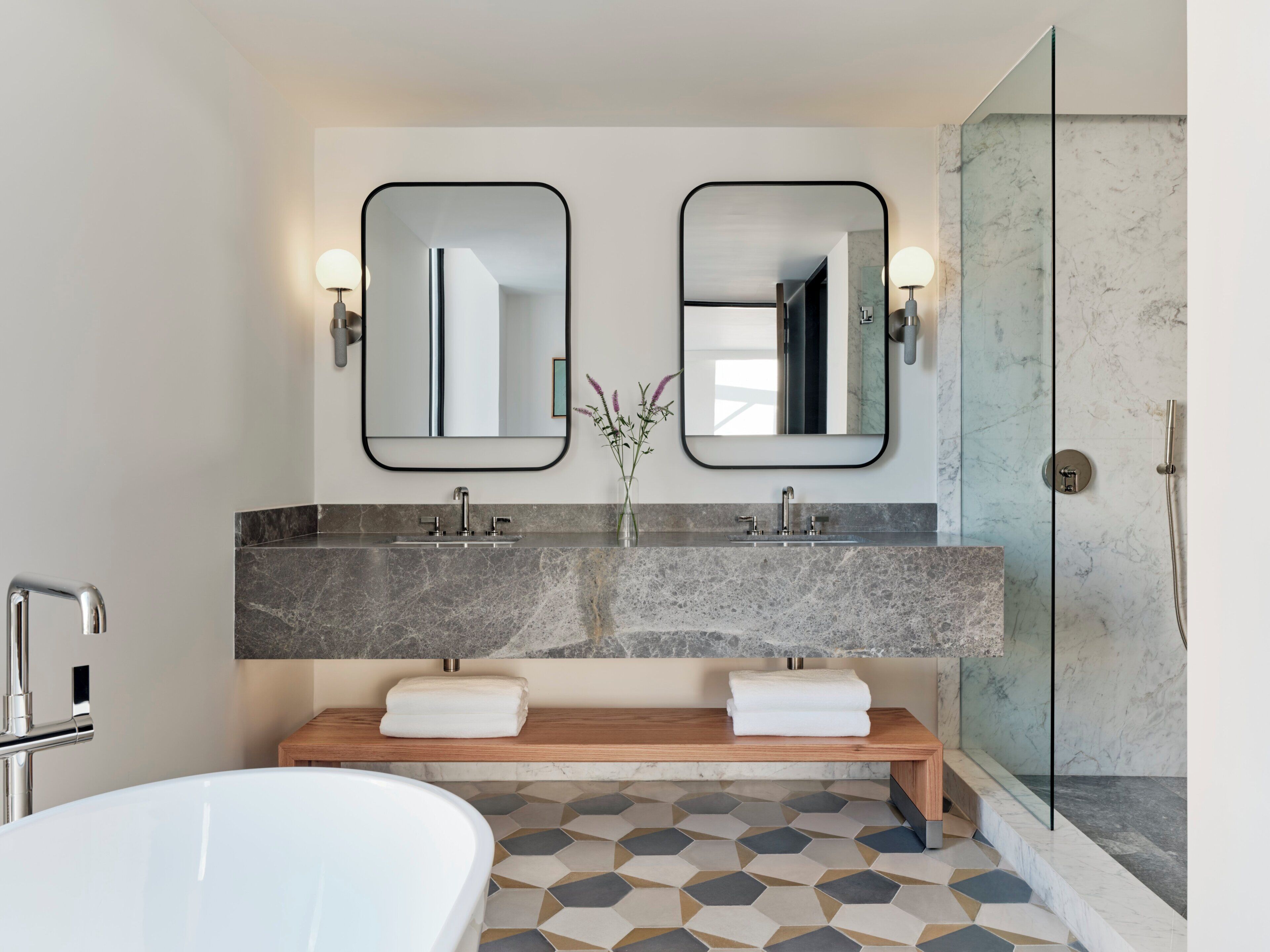 A modern bathroom with a freestanding bathtub, a double vanity with two sinks, and a glass-enclosed shower.