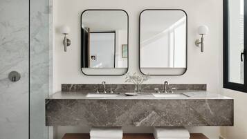 Une salle de bain moderne avec deux vasques, des plans de travail en marbre et des miroirs fixés au mur.