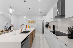 A modern kitchen with a central island, stainless steel appliances, and pendant lighting. - Beachfront Paradise: Townhome w/ Pool and Rooftop (Pompano Beach)