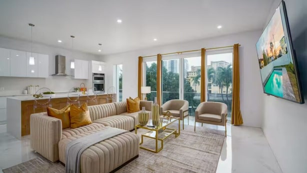 Ein modernes Wohnzimmer mit einer Couch, Sesseln, einem Couchtisch und einem großen Fenster mit Blick.