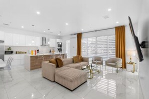 A modern living room with a sofa, a coffee table, and a TV. - Beachfront Paradise: Townhome w/ Pool and Rooftop (Pompano Beach)