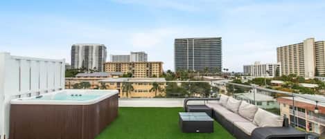 Terraza en la azotea con jacuzzi, mobiliario exterior y vistas a la ciudad.