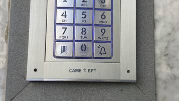 Ein Tastenfeld mit Zahlen und Buchstaben, ein Navigationsfeld sowie ein Schild mit der Aufschrift 'CAME BPT'.