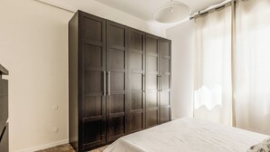 Un dormitorio con un armario grande, una cama con cubrecama blanco y una lámpara sobre la cama.