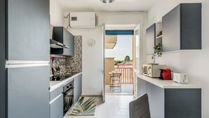 Cocina compacta con microondas, tostadora y un pequeño comedor con una silla y mesa.