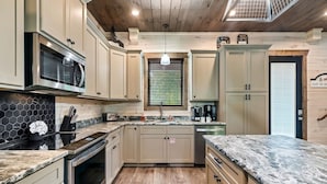 Una cocina moderna con armarios de madera, encimera de granito, horno empotrado y una ventana con persianas.