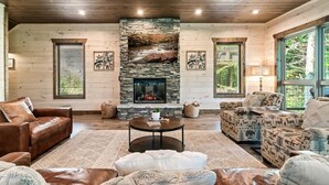Un salón acogedor con chimenea de piedra, paredes de madera y asientos cómodos.