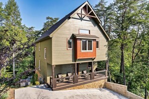 Une cabane en bois à deux étages, dotée d’un balcon et entourée d’arbres.