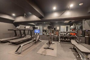 Een sportschool met loopbanden, elliptische trainers en een roeimachine.