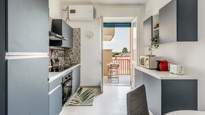 A compact kitchen with grey cabinets, a microwave, a toaster, and a small dining area with a table and chairs. - Maristella Holiday House (Pregnana Milanese)