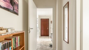 A hallway with a wooden bookshelf, a mirror, and a door leading to another room. - Maristella Holiday House (Pregnana Milanese)