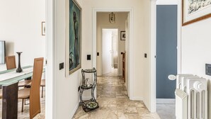 A hallway with a dining area on the left, a pet carrier, and a radiator on the right. - Maristella Holiday House (Pregnana Milanese)