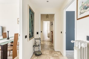 A hallway with a dining area on the left, a pet carrier, and a radiator on the right.