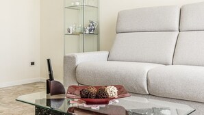 A modern living room with a grey sofa, a glass coffee table with decorative items, and a glass cabinet with kitchenware. - Maristella Holiday House (Pregnana Milanese)
