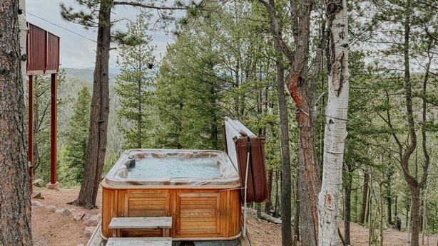 Ein Whirlpool in einer bewaldeten Gegend mit einer Holzterrasse und Stufen, die zu ihm hinaufführen.