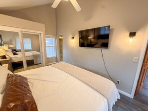 A bedroom with a bed, a TV mounted on the wall, and a desk with a chair. - Sunset Ridge Escape with Hot Tub & Incredible Mountain Views (Divide)