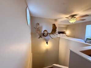 A hotel room with a bed, a ceiling fan, a wall-mounted light, and a decorative antler piece. - Sunset Ridge Escape with Hot Tub & Incredible Mountain Views (Divide)