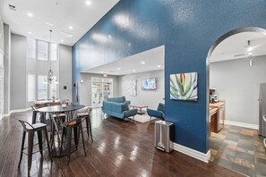Ein geräumiger Raum mit Essbereich, blauen Sofas und Kunstwerken an den Wänden.