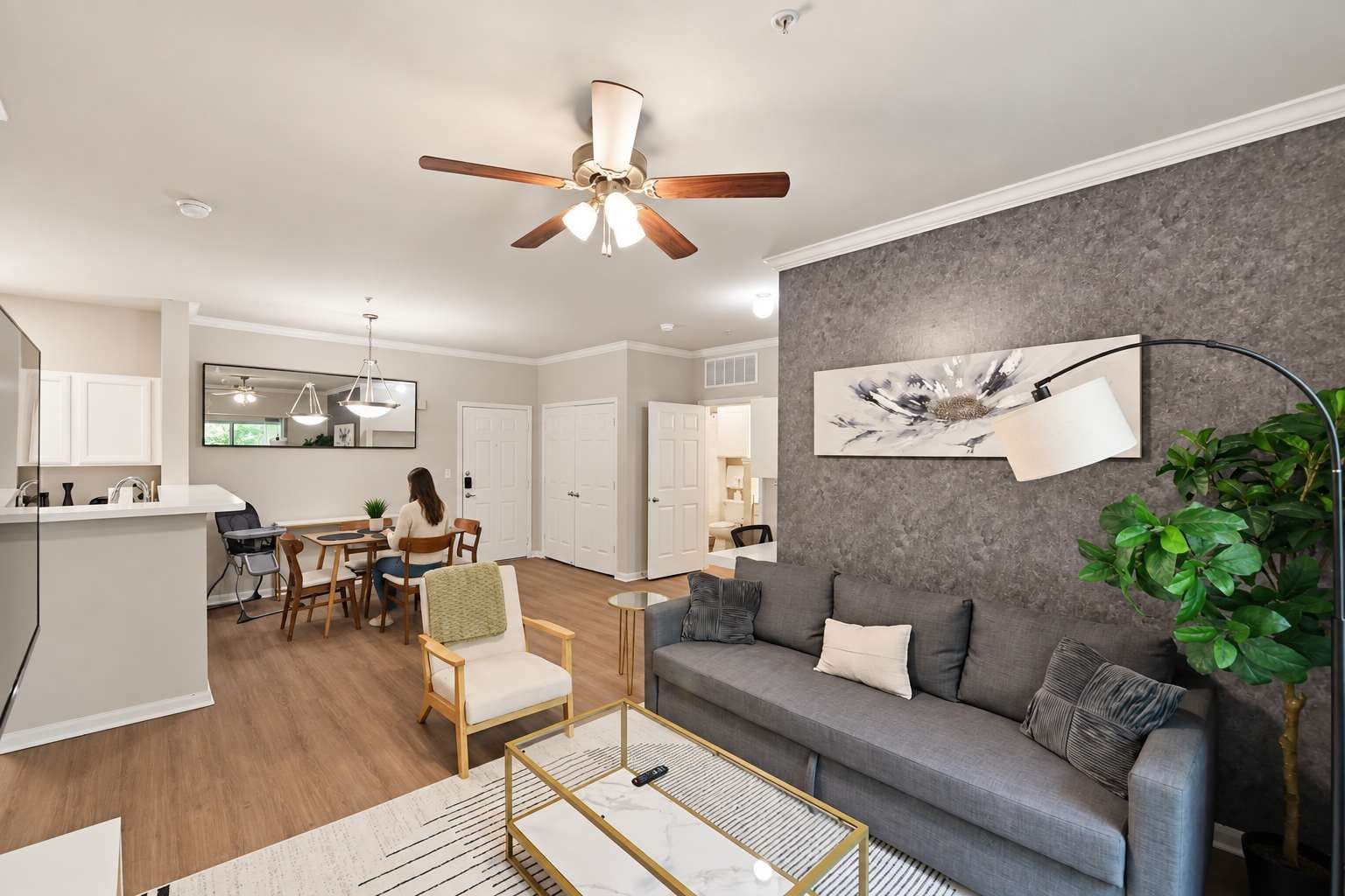 A modern living room with a grey sofa, a coffee table, and a dining area with chairs and a table.