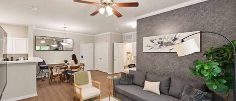 A modern living room with a grey sofa, a coffee table, and a dining area with chairs and a table.