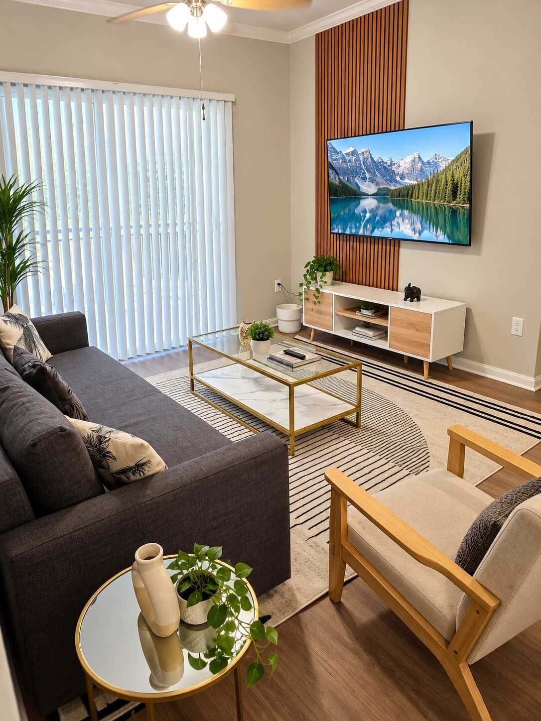 Un salon moderne avec un canapé, une table basse, un téléviseur et des plantes décoratives.