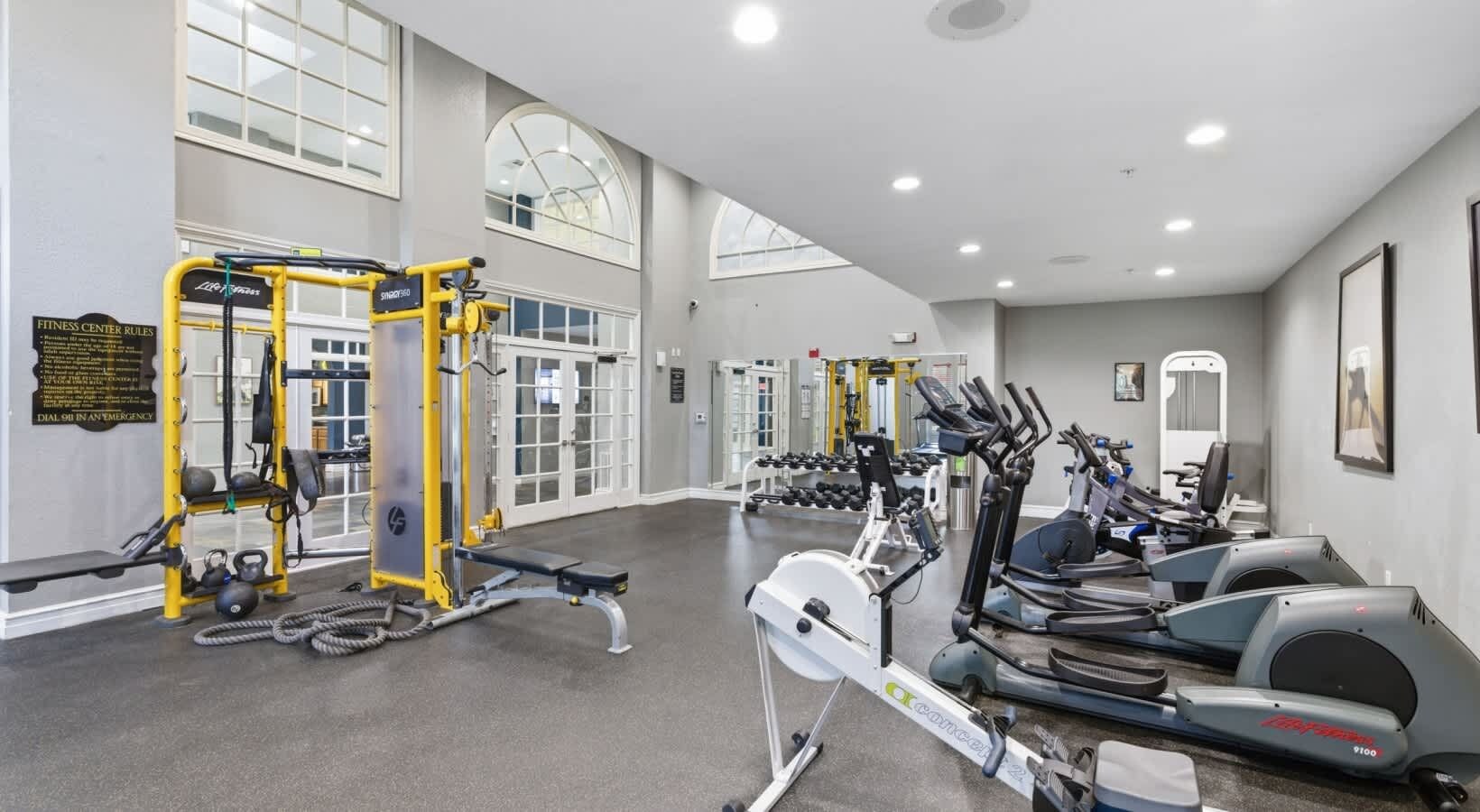 Un gimnasio con máquinas de cardio, equipo de levantamiento de pesas y una prensa de banca.