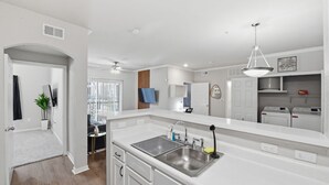 A modern kitchen with a large island, built-in appliances, and a dining area with a small table and chairs. - Modern Dallas Stay Near Love Field and Pool (Dallas)
