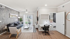 A modern living room with a sofa, coffee table, and TV. - Modern Dallas Stay Near Love Field and Pool (Dallas)
