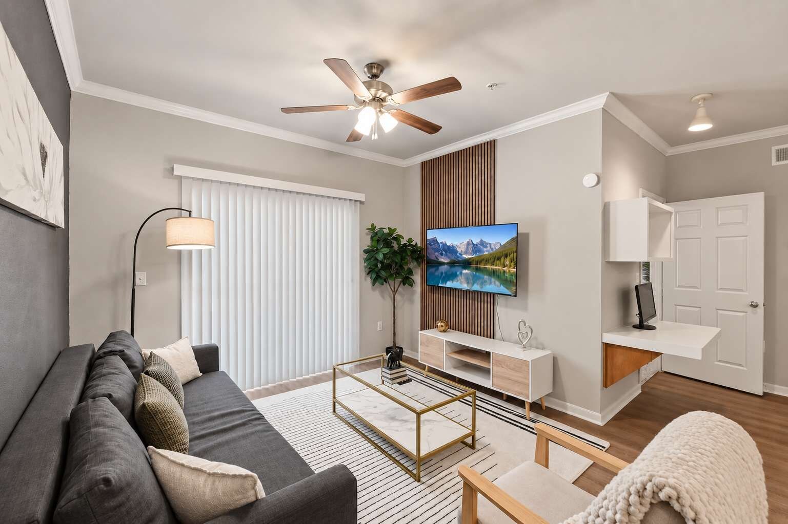 A modern living room with a sofa, coffee table, TV, and a ceiling fan.