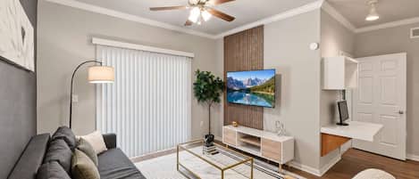 A modern living room with a sofa, coffee table, TV, and a ceiling fan.