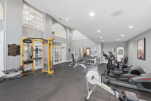 A gym with exercise equipment, a sign with emergency instructions, and large windows. - Spacious Dallas 2BR Near Downtown & Love Field (Dallas)