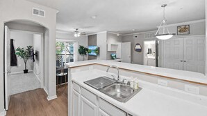 Una cocina moderna con armarios blancos, un lavamanos de acero inoxidable y un ventilador de techo.