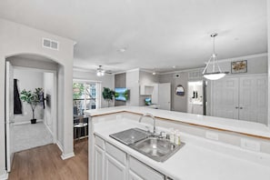 A modern kitchen with white cabinetry, a stainless steel sink, and a ceiling fan. - Spacious Dallas 2BR Near Downtown & Love Field (Dallas)