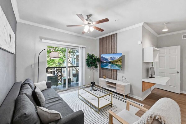 A modern living room with a sofa, TV, and a ceiling fan. - Spacious Dallas 2BR Near Downtown & Love Field (Dallas)