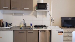 A compact kitchenette with a microwave, sink, and a small refrigerator.
