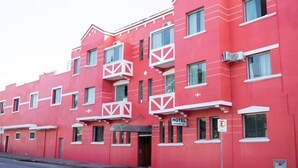 A red hotel building with balconies, a sign indicating it's a hotel, and a no parking sign.