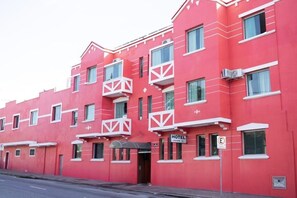 A red hotel building with balconies, a sign indicating it's a hotel, and a no parking sign. - Campos Gerais Hotel (Belo Horizonte)