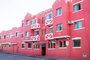 Un edificio de hotel rojo con balcones, una señal que indica que es un hotel y un letrero de no estacionamiento.