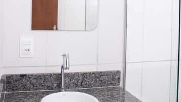 Un baño con encimera de granito, lavabo blanco y espejo.