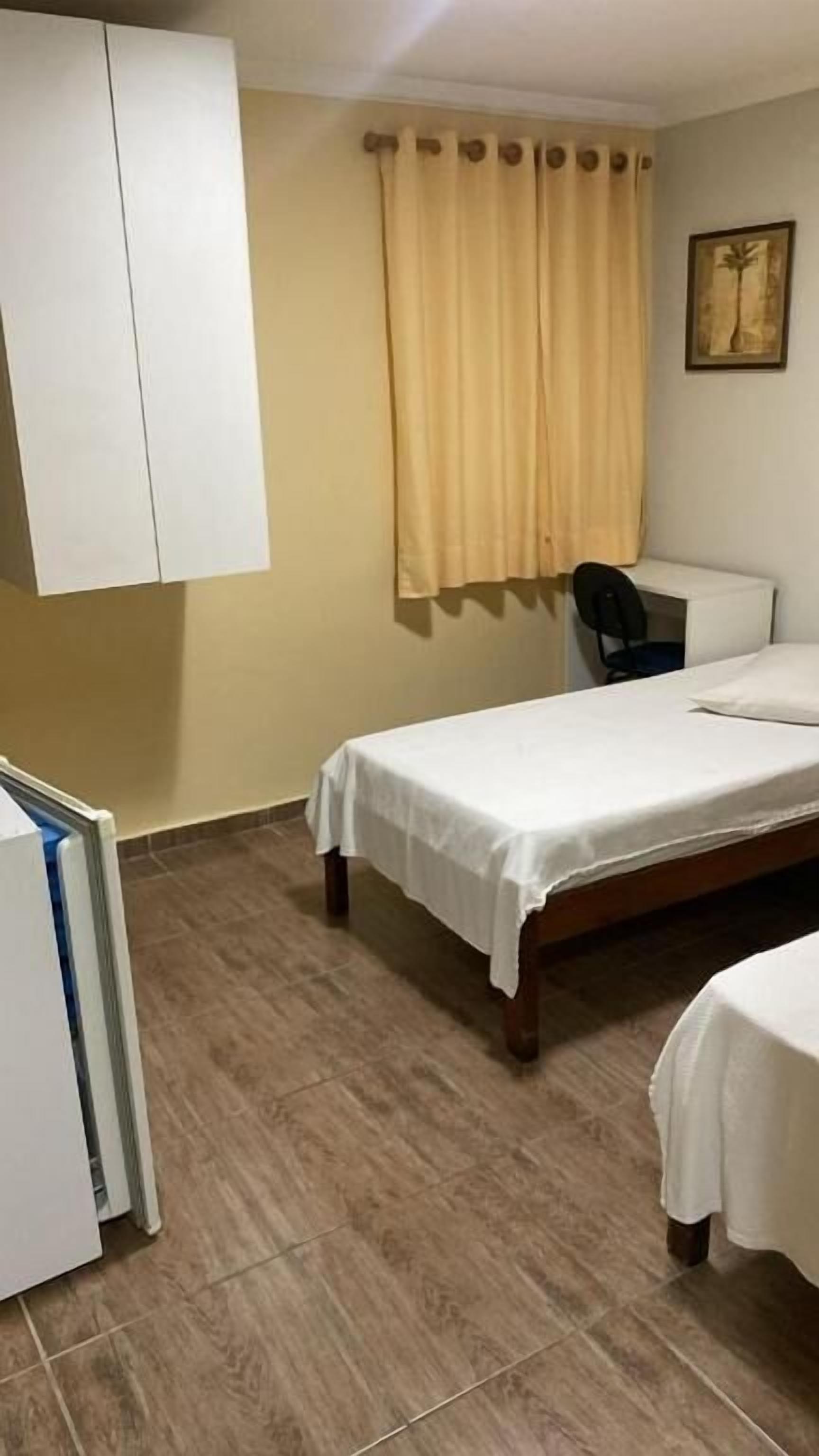 A bedroom with a bed, a desk, a chair, and a wardrobe.