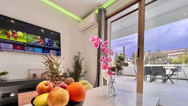 Une chambre d’hôtel moderne dotée d’un grand téléviseur à écran plat, d’un panier de fruits sur la table et offrant une vue sur l’extérieur par la fenêtre.