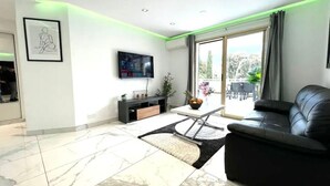Un salon moderne avec un canapé, un téléviseur à écran plat, une table basse et une grande fenêtre donnant sur un beau paysage.